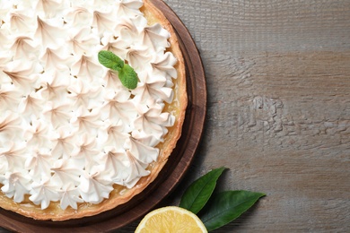 Photo of Delicious lemon meringue pie on wooden table, flat lay. Space for text