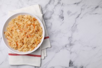 Photo of Bowl with tasty sauerkraut on white marble table, top view. Space for text