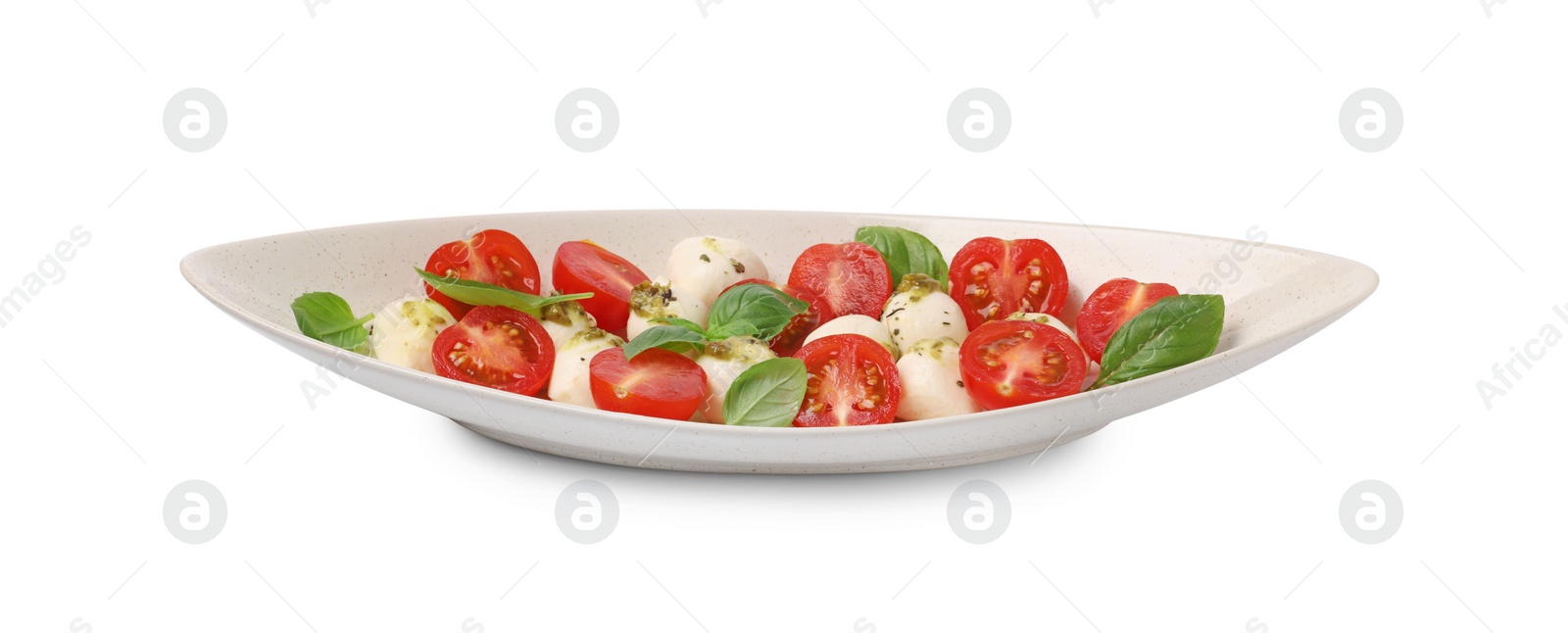 Photo of Plate of tasty Caprese salad with mozzarella, tomatoes, basil and pesto sauce isolated on white