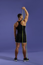 Photo of Muscular man exercising with elastic resistance band on purple background, back view