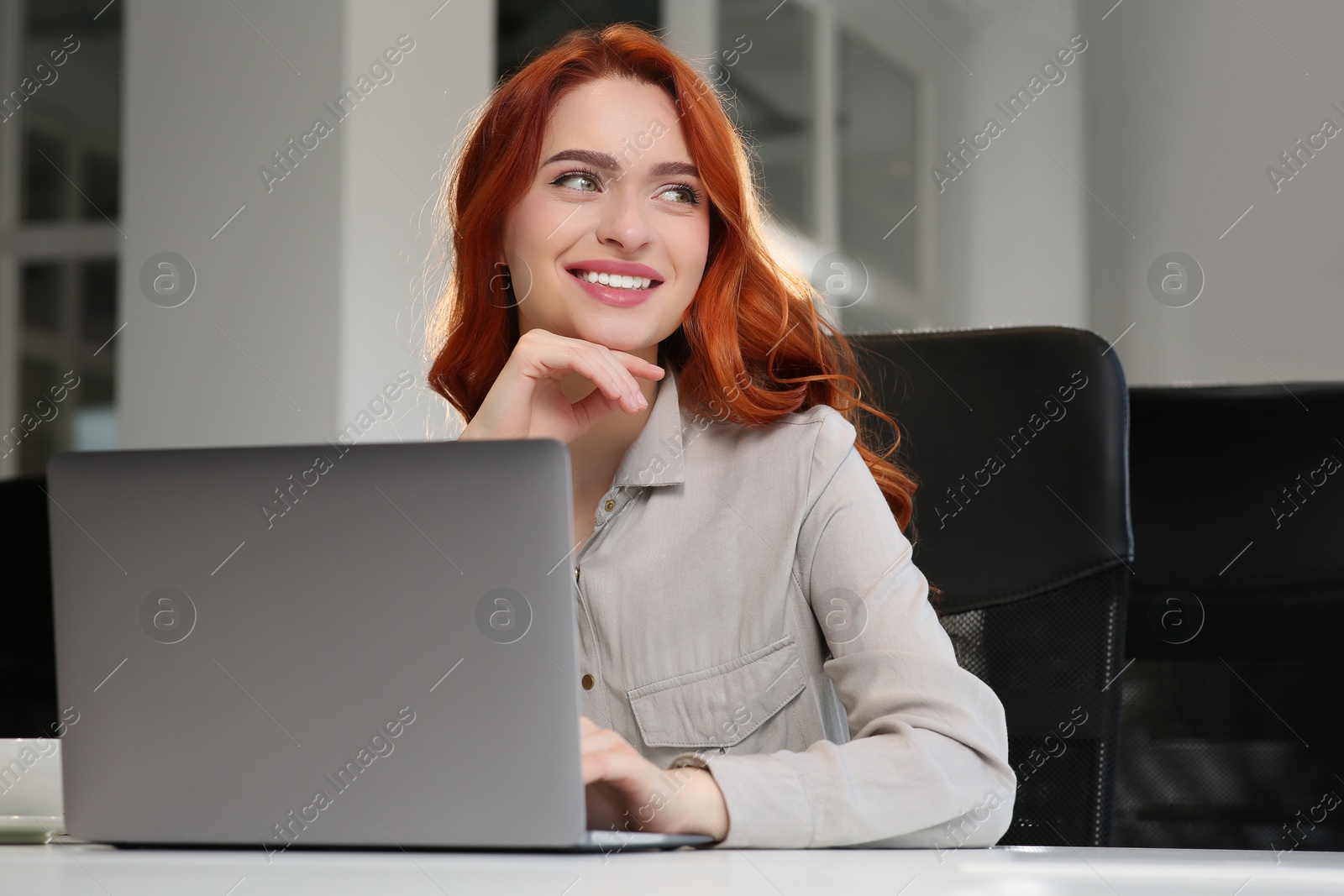 Photo of Happy woman working with laptop at white desk in office