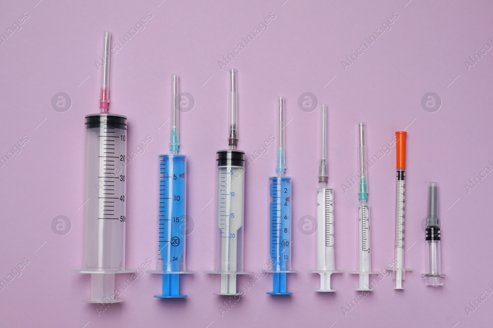 Photo of Disposable syringes with needles on violet background, flat lay
