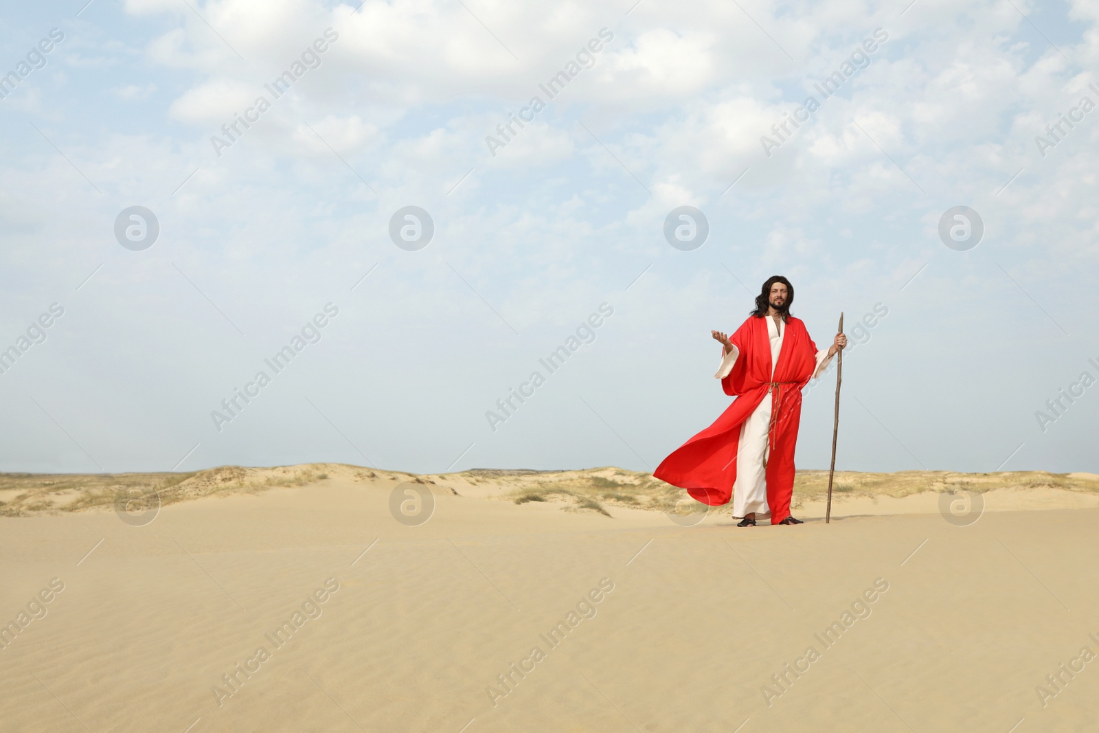 Photo of Jesus Christ walking with stick in desert. Space for text