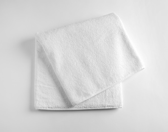Photo of Folded soft terry towel on light background, top view