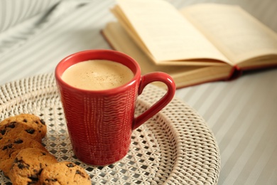 Cup of aromatic coffee, cookies and book on soft blanket