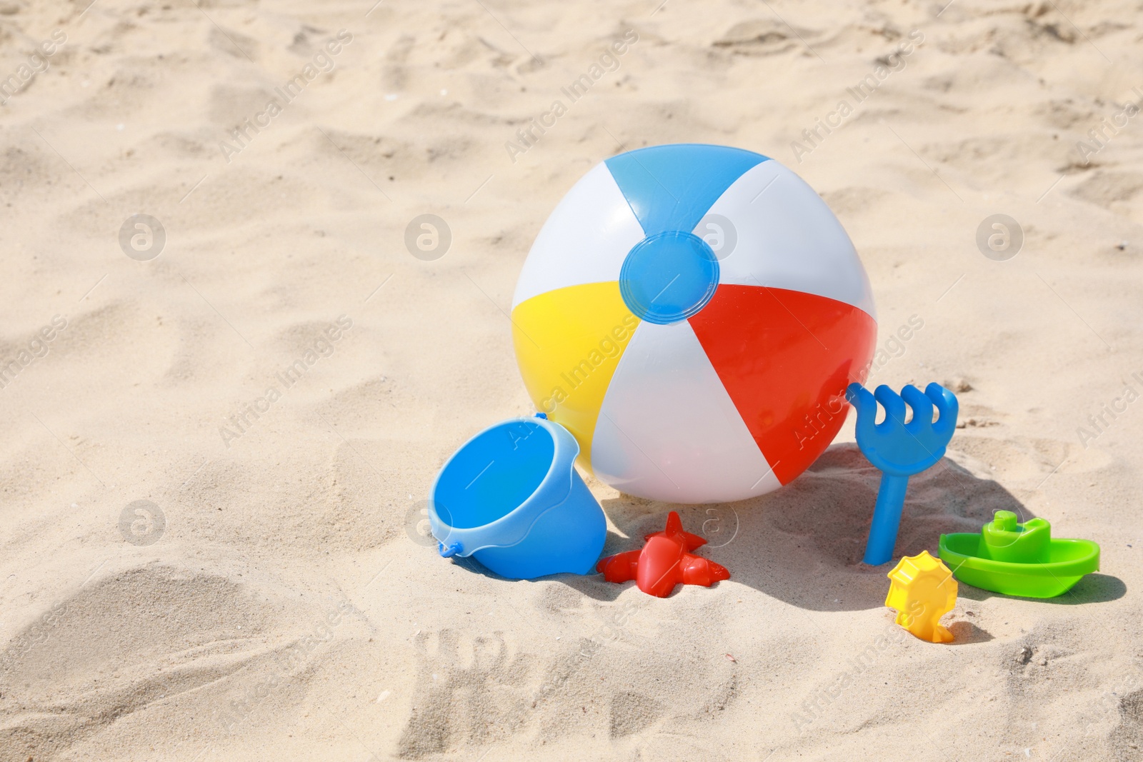 Photo of Different beach toys and inflatable ball on sand outdoors, space for text