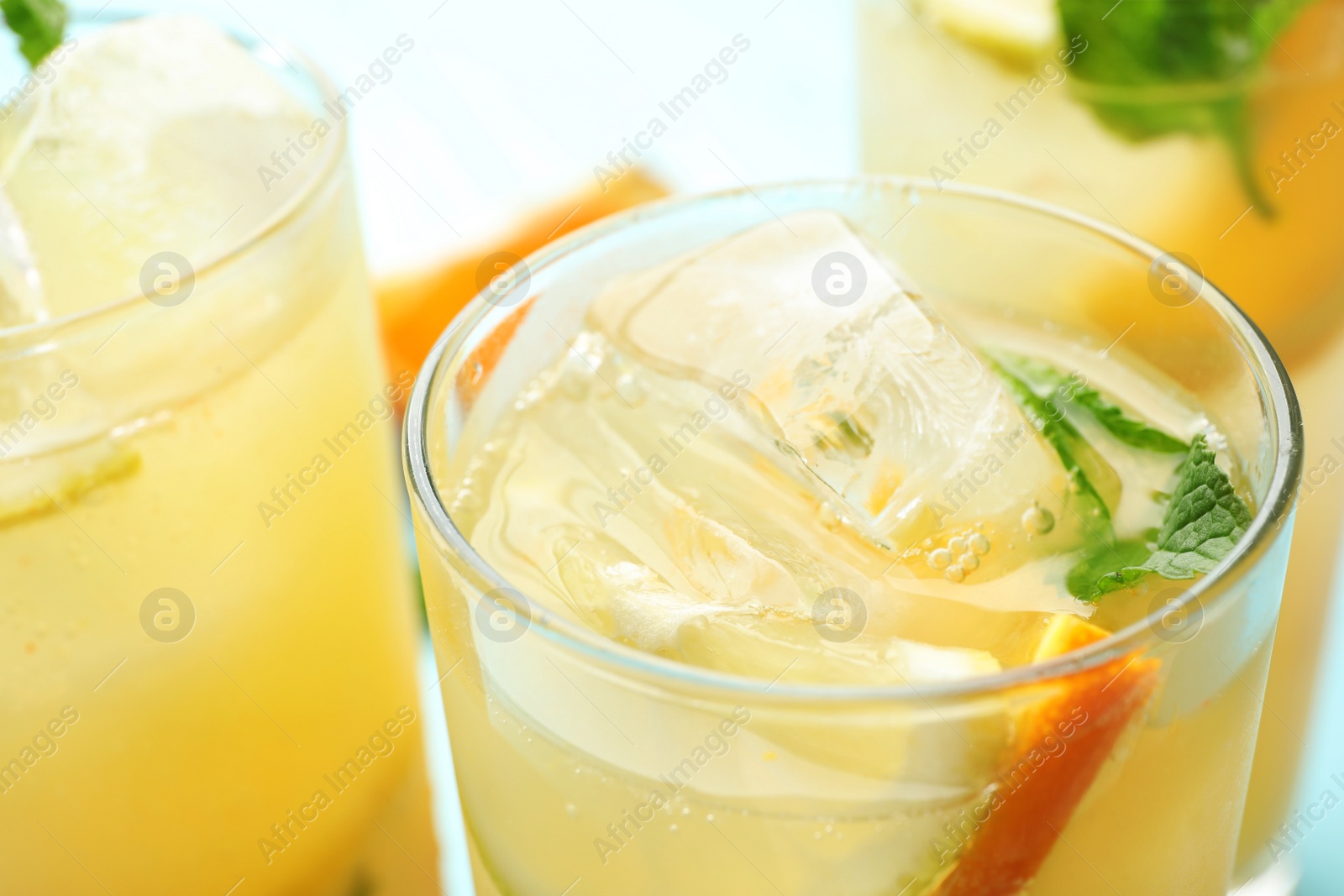 Photo of Glasses of citrus refreshing drink with ice cubes and mint, closeup