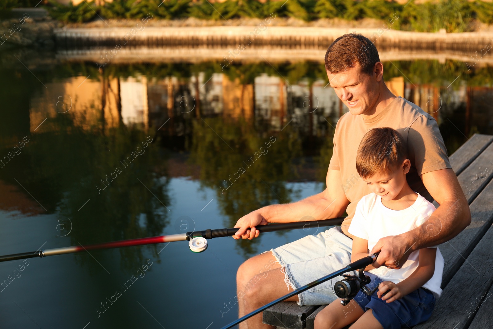 Photo of Dad and son fishing together on sunny day