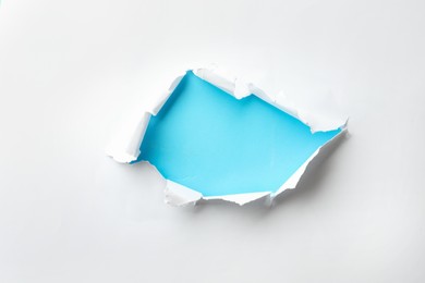 Photo of Hole in white paper on light blue background