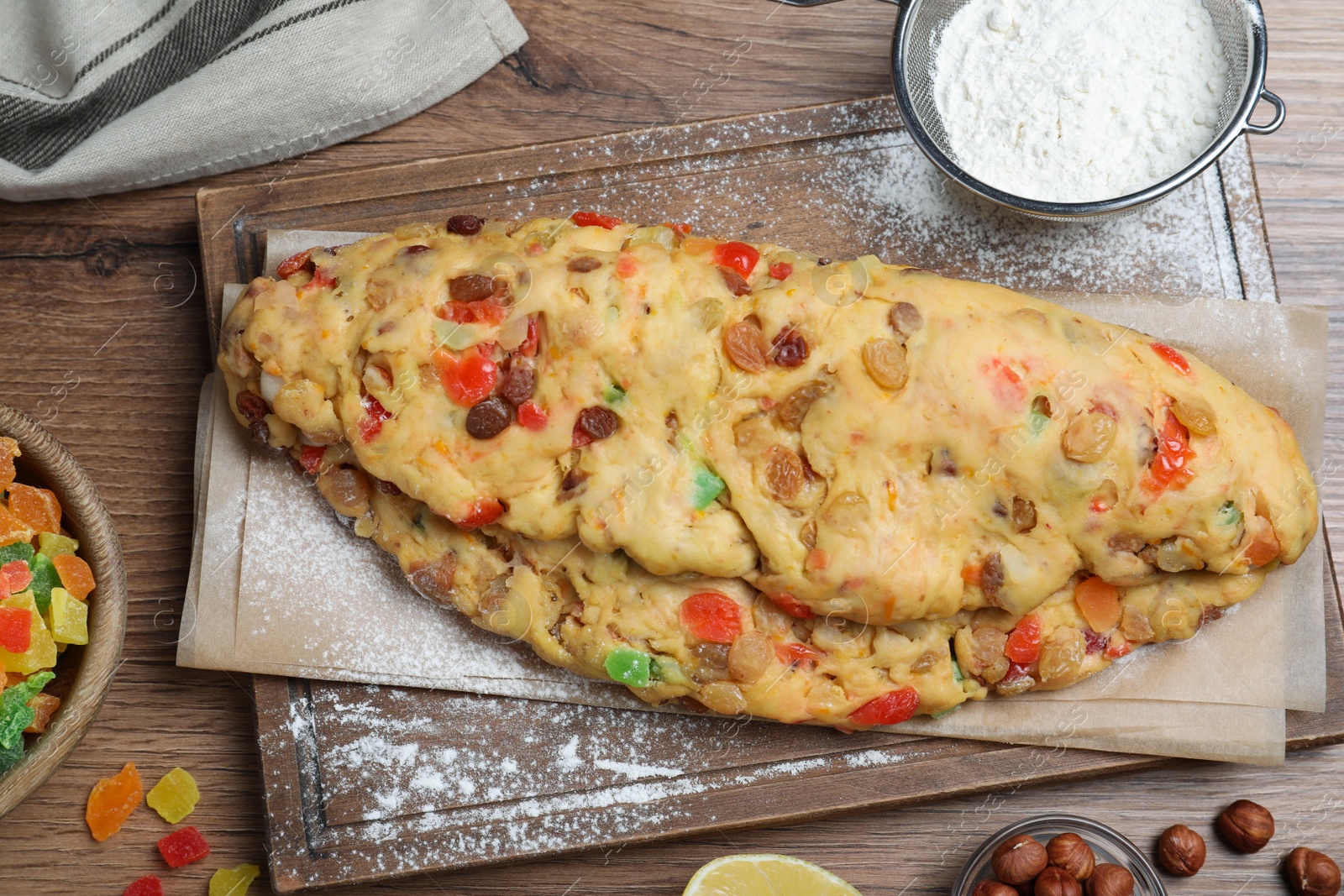 Photo of Unbaked Stollen with candied fruits and raisins on wooden table, flat lay