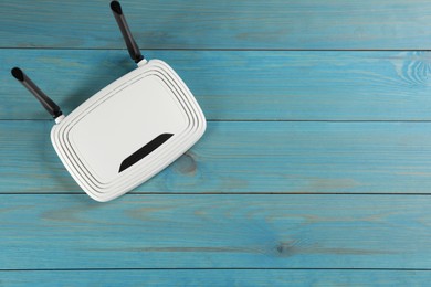 Photo of Modern Wi-Fi router on light blue wooden background, top view. Space for text