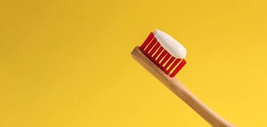 Brush with toothpaste on yellow background, space for text. Banner design