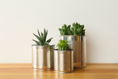Houseplants in tin cans on wooden table