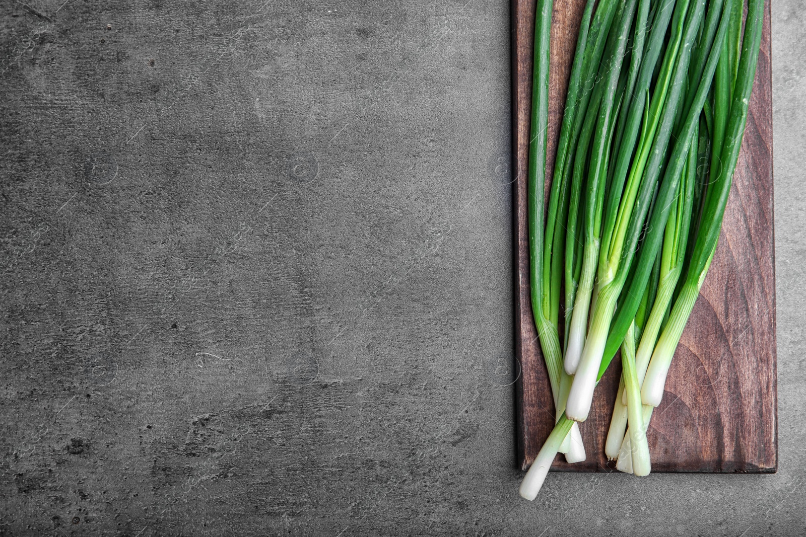 Photo of Wooden board with fresh green onion on table, top view