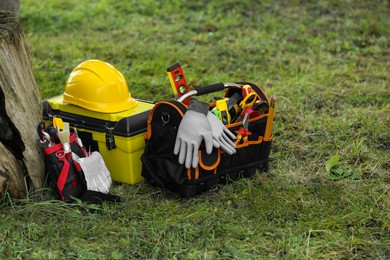 Bag, belt and box with different tools for repair on grass near tree outdoors