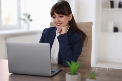 Woman watching webinar at wooden table in office