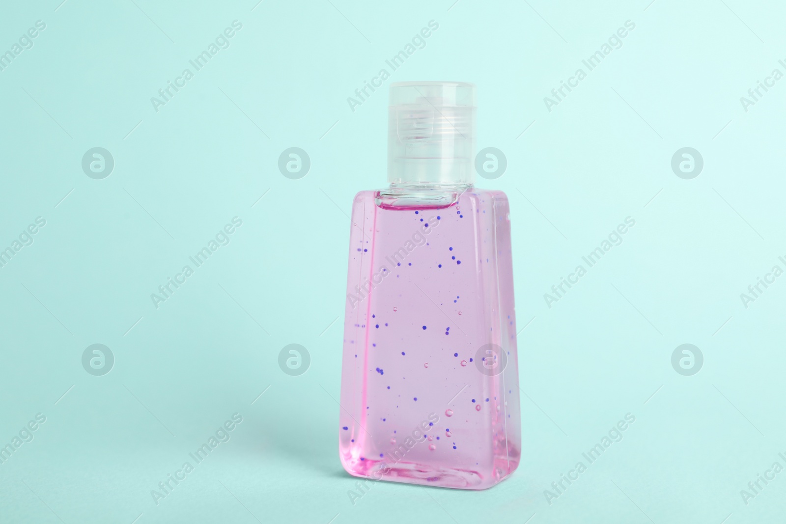 Photo of Bottle with antiseptic gel on light blue background