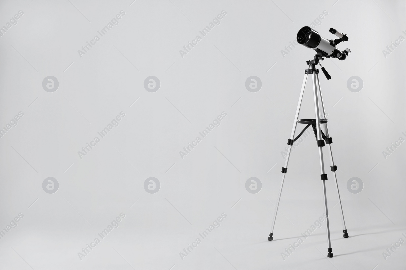 Photo of Tripod with modern telescope on light grey background. Space for text