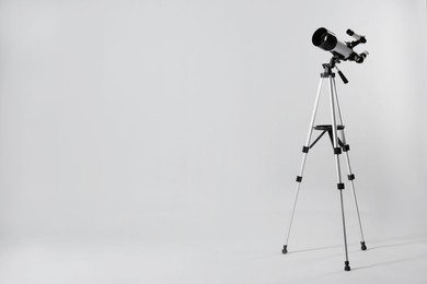 Tripod with modern telescope on light grey background. Space for text