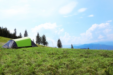 Photo of Small camping tent in mountains on sunny day