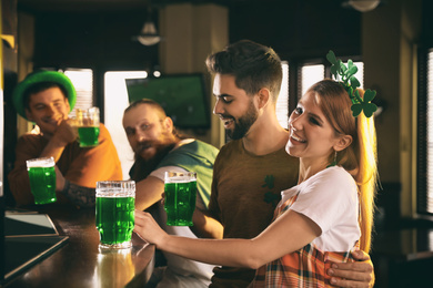 Photo of Group of friends with glasses of green beer in pub. St. Patrick's Day celebration