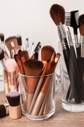 Set of professional makeup brushes on wooden table