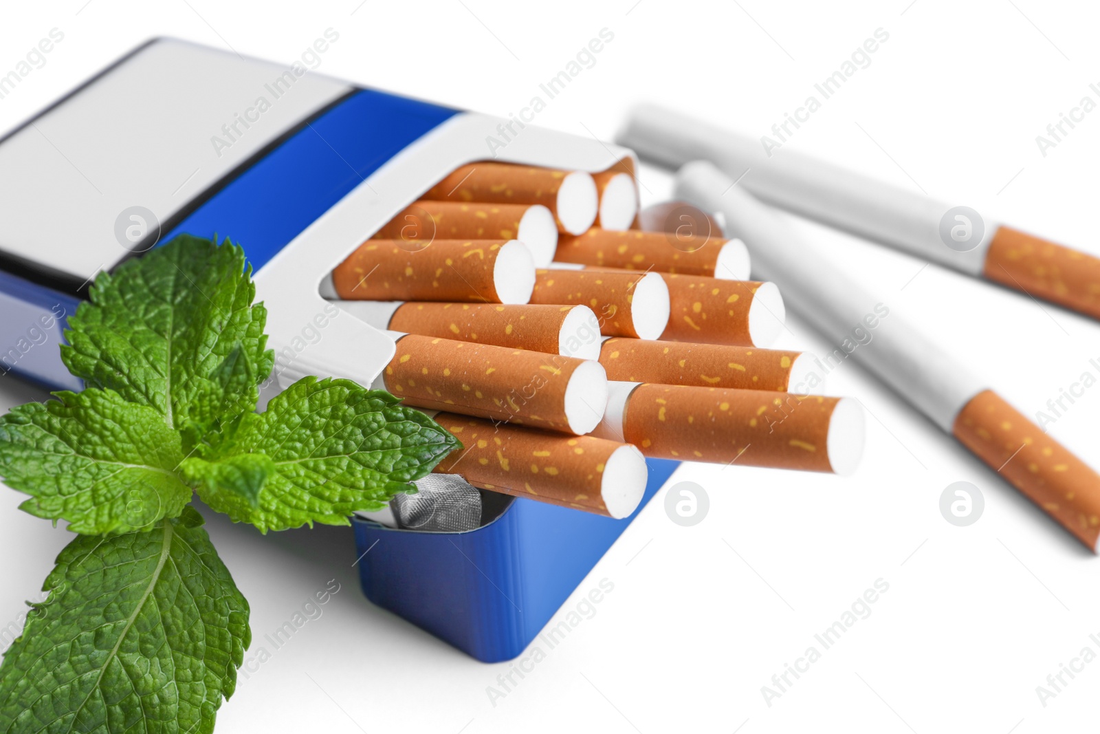 Photo of Pack of menthol cigarettes and fresh mint leaves on white background, closeup