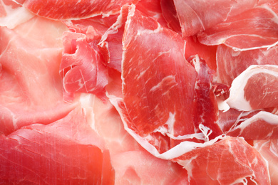 Tasty prosciutto slices as background, closeup view