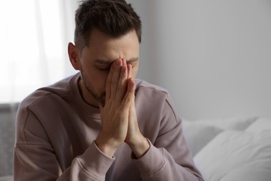 Photo of Upset man sulking at home, space for text. Loneliness concept