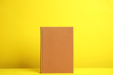 Photo of Hardcover book on yellow background. Space for design