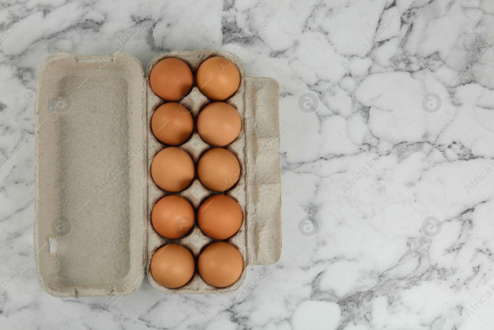 Photo of Raw chicken eggs on white marble table, top view. Space for text