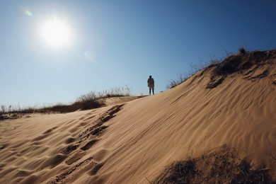 Photo of Man in desert on sunny day, back view