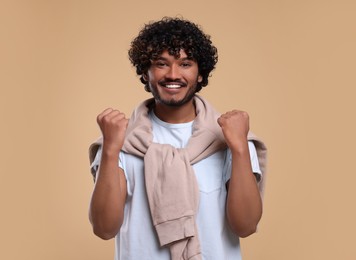 Photo of Handsome young happy man on beige background
