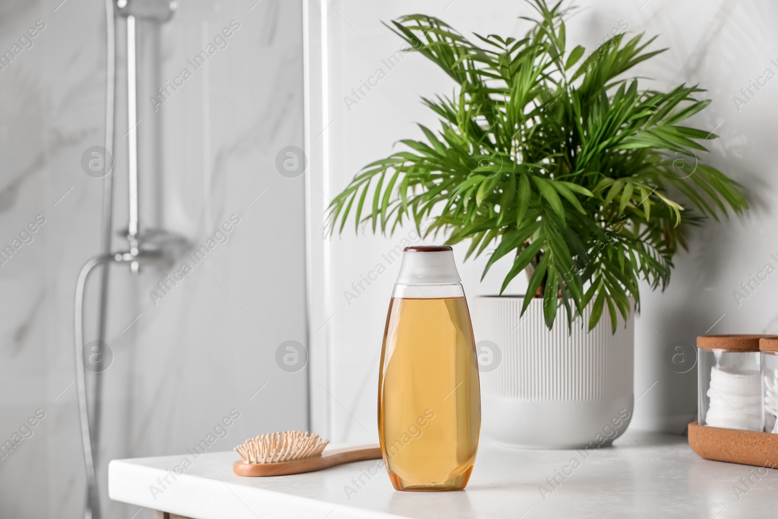 Photo of Bottle of shampoo and hairbrush on white table near shower stall in bathroom, space for text