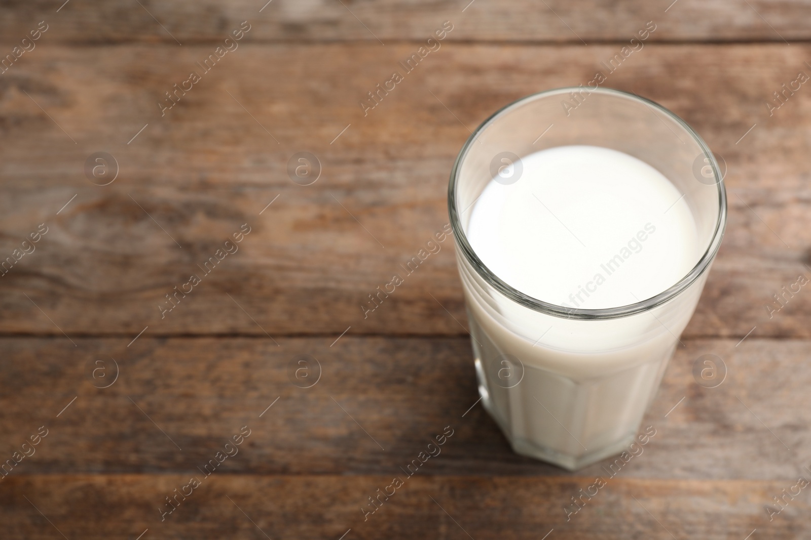 Photo of Glass of fresh milk on wooden table. Space for text