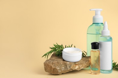 Bottles with cosmetic products, stone and rosemary on beige background. Space for text
