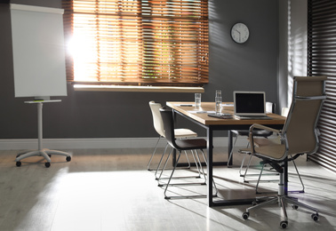 Photo of Stylish office interior with wooden table and flipchart