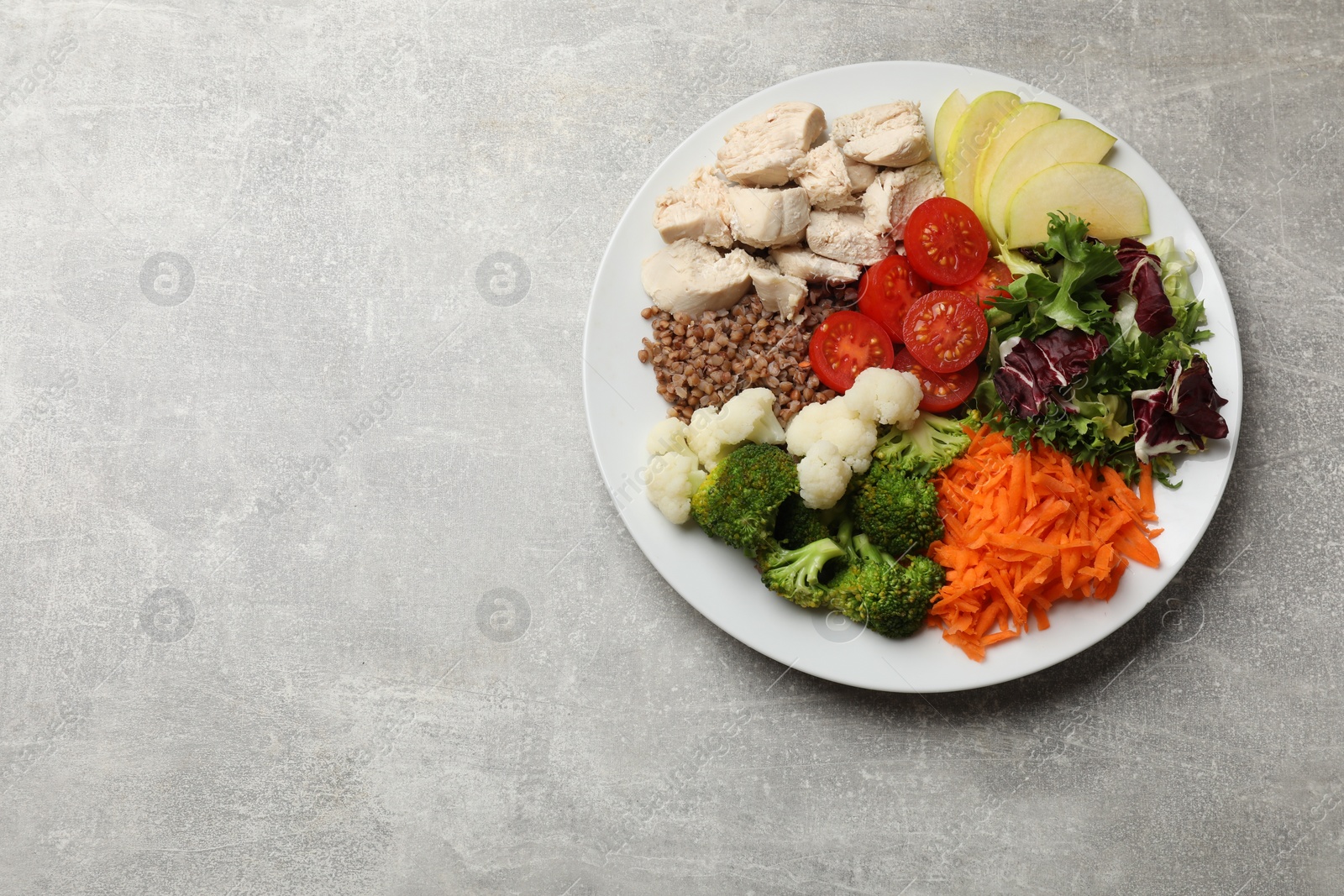 Photo of Balanced diet and healthy foods. Plate with different delicious products on grey table, top view. Space for text