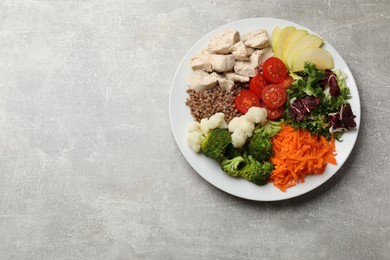 Photo of Balanced diet and healthy foods. Plate with different delicious products on grey table, top view. Space for text