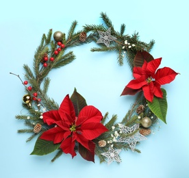 Photo of Beautiful wreath with poinsettia on light cyan background, flat lay, space for text. Christmas traditional flower