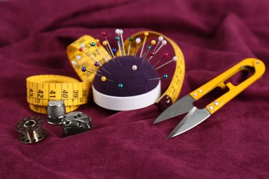 Photo of Composition with different sewing items on wine red fabric