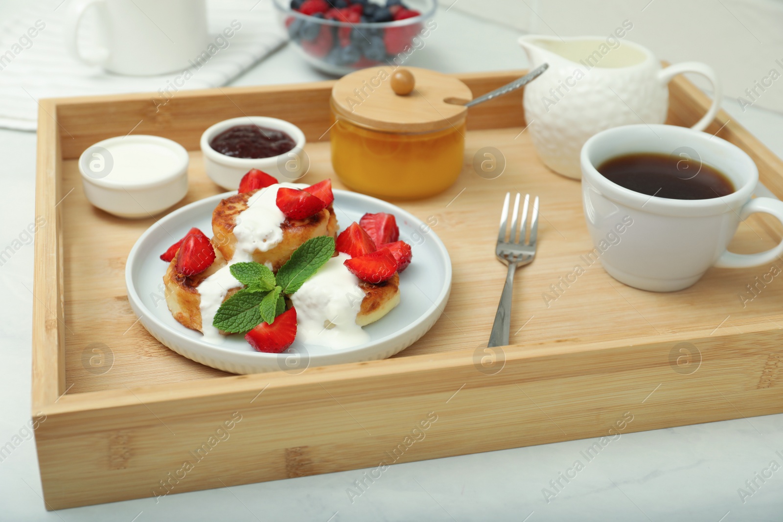 Photo of Delicious cottage cheese pancakes with fresh strawberries  sour cream and mint served on wooden tray