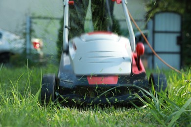 Image of Man cutting grass with lawn mower in garden, closeup