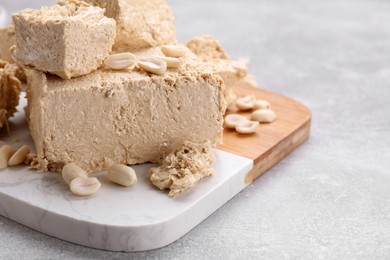 Pieces of tasty halva on light gray table, closeup. Space for text