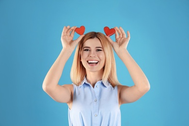 Portrait of beautiful woman holding decorative hearts on color background