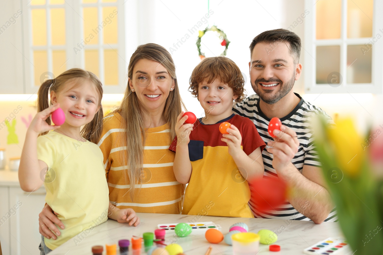 Photo of Easter celebration. Portrait of happy family with painted eggs at white marble table in kitchen