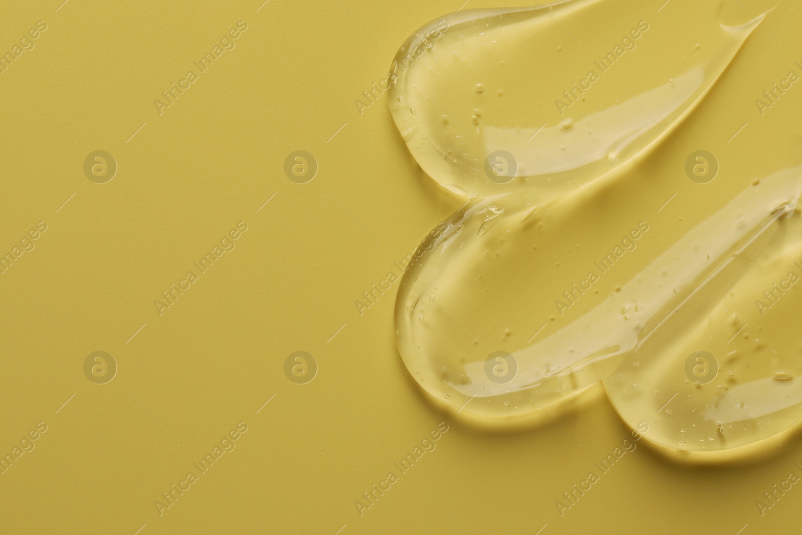 Photo of Sample of clear cosmetic gel on yellow background, top view. Space for text