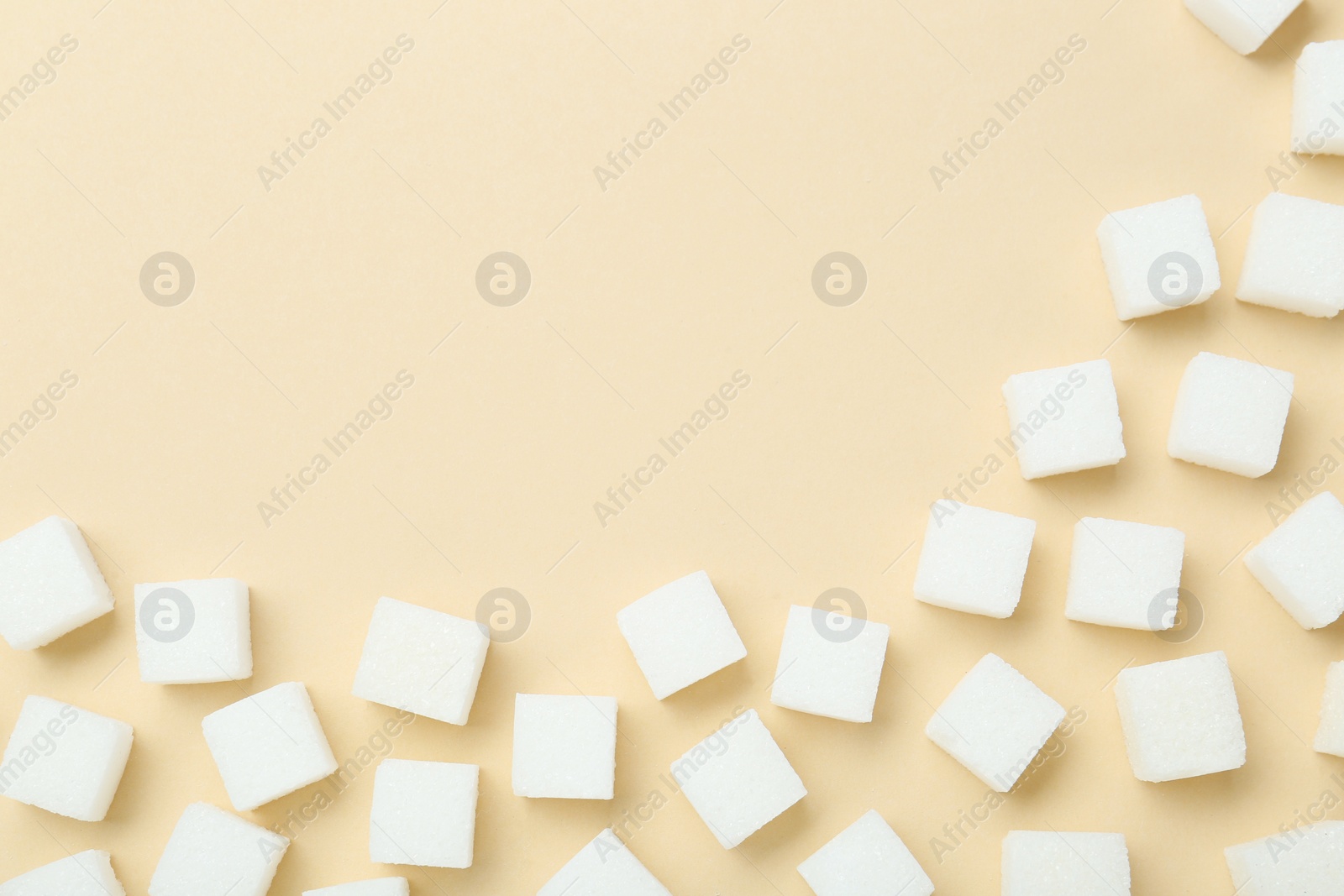 Photo of White sugar cubes on beige background, top view. Space for text