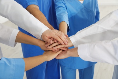 Photo of Team of medical workers holding hands together, closeup. Unity concept