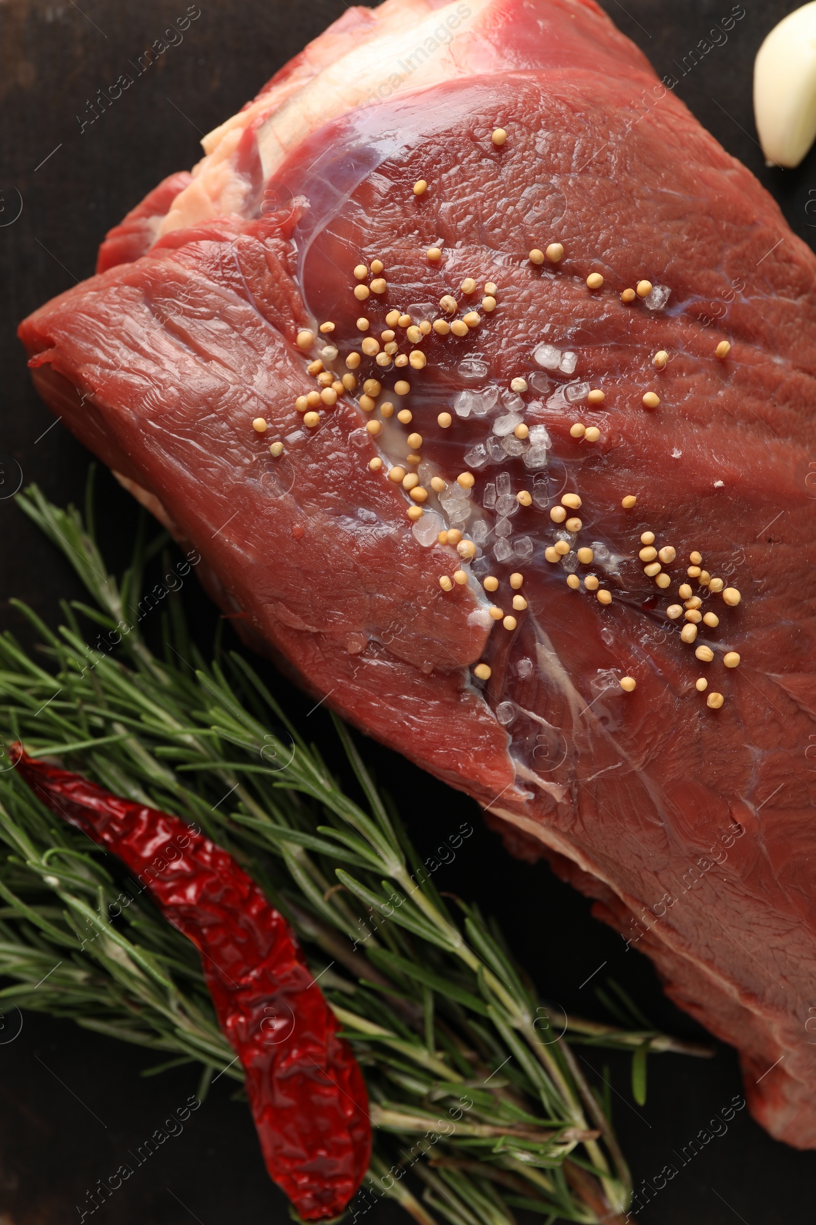 Photo of Piece of raw beef meat, rosemary, spices and chili pepper on table, flat lay